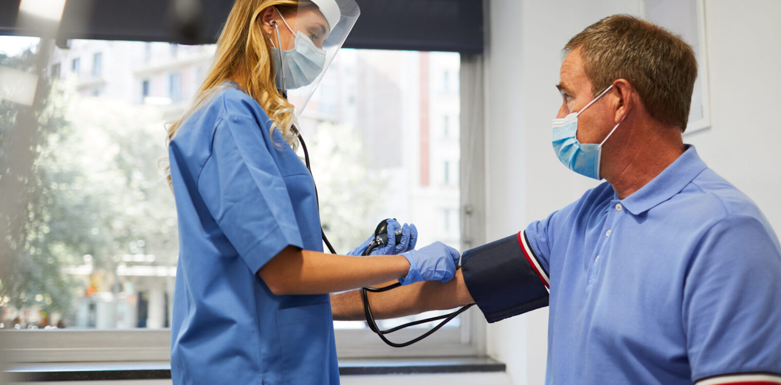 A nurse checking blood pressure off a senior man.