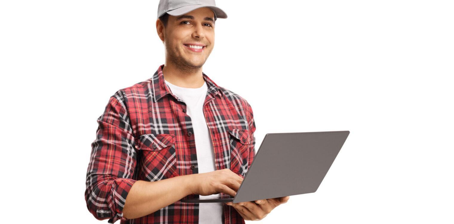 Young man with a cap holding a laptop computer and smiling at the camera